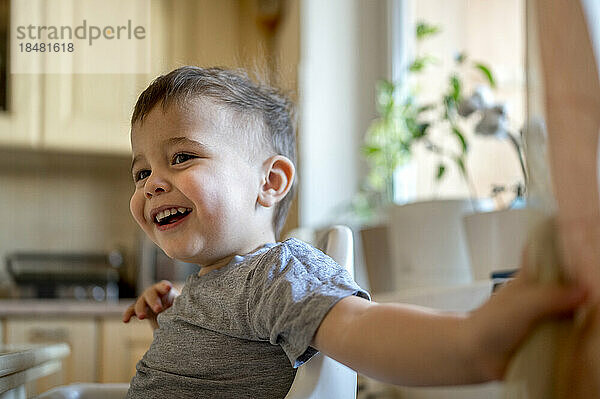 Happy boy sitting in kitchen at home