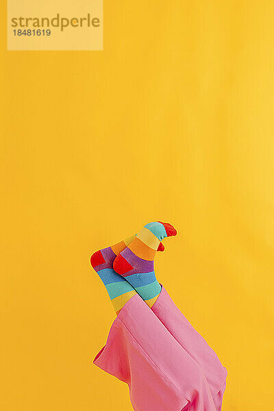 Feet of woman with colorful socks over yellow background