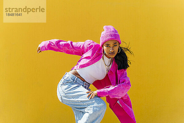 Hip-Hop-Tänzer tanzt an einem sonnigen Tag vor einer gelben Wand