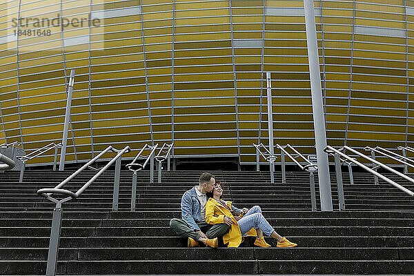 Mann küsst Frau auf der Treppe vor dem Stadion
