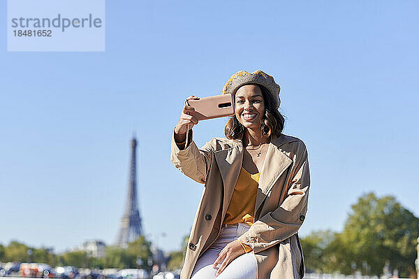 Glückliche junge Frau  die ein Selfie mit ihrem Smartphone über blauem Himmel macht