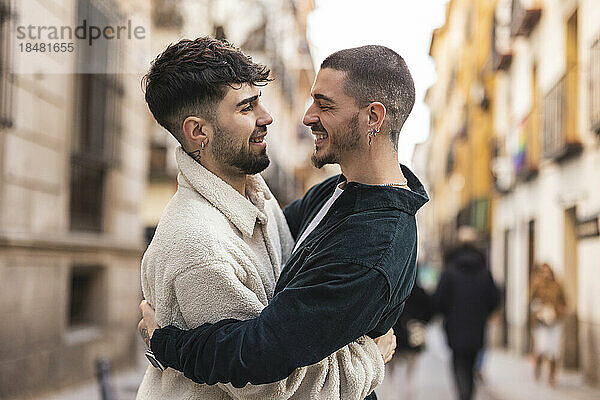 Glücklicher schwuler Mann umarmt seinen Freund auf der Straße
