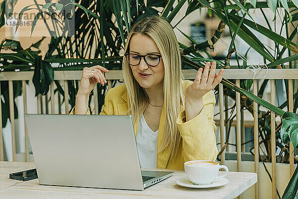 Geschäftsfrau macht Videoanruf am Laptop und sitzt im Café