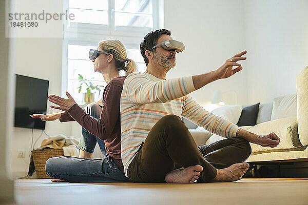 Älteres Paar trägt ein Virtual-Reality-Headset und gestikuliert zu Hause