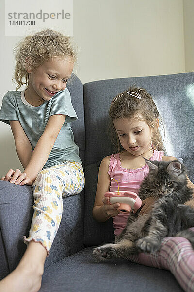 Mädchen spielen zu Hause mit Katze und Kamera