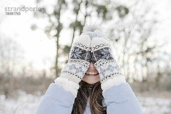 Happy girl wearing mittens covering eyes