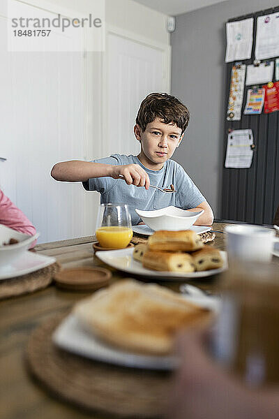 Boy having breakfast at table at home