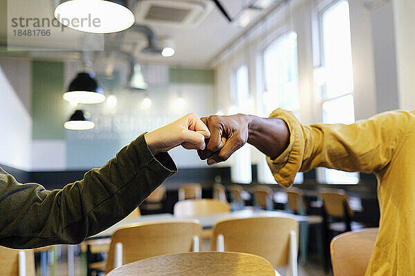 Hands of business colleagues giving fist bump at office