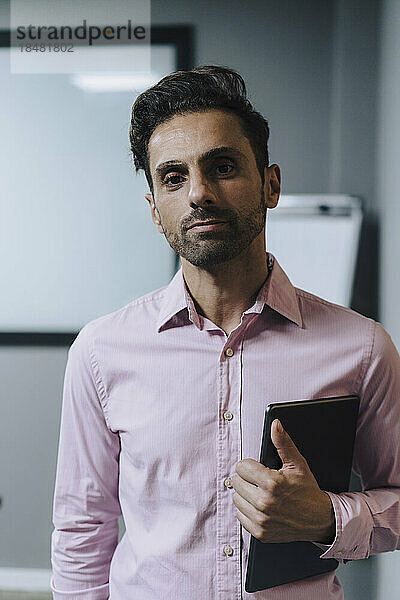 Reifer Geschäftsmann steht mit Tablet-PC im Büro