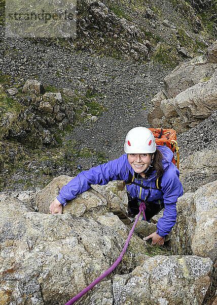 Happy woman wearing helmet climbing rock  Lake District  England