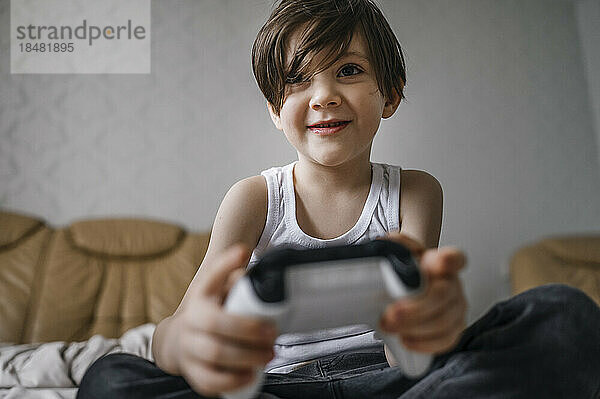 Glücklicher Junge mit Controller  der zu Hause Videospiele spielt