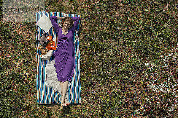 Smiling young woman relaxing on mattress at garden