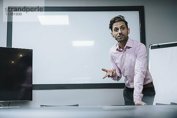 Mature businessman giving presentation in front of blank whiteboard at office
