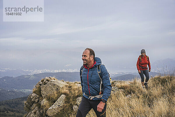 Lächelnder Mann und Frau beim Wandern auf dem Berg