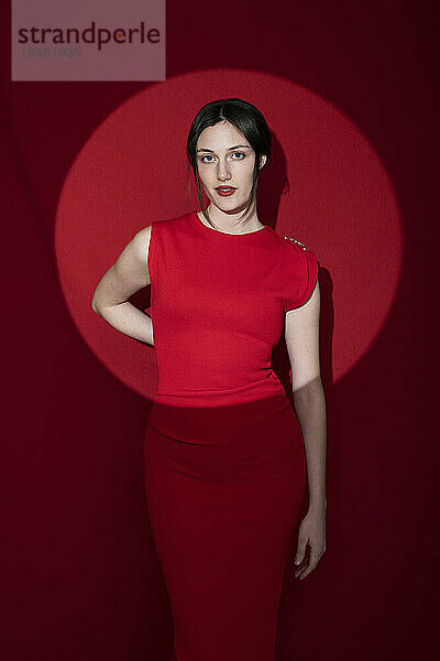 Schöne junge Frau im Kleid vor rotem Hintergrund
