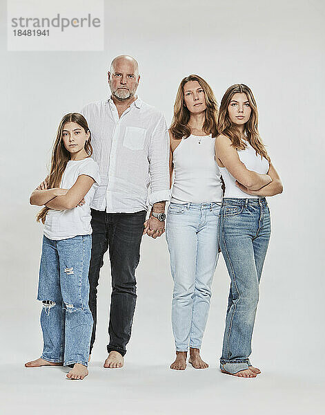 Selbstbewusste Eltern stehen mit ihren Töchtern vor weißem Hintergrund