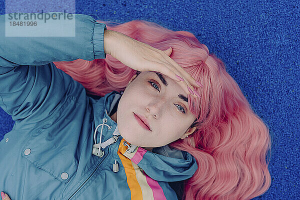 Woman with pink hair lying on blue surface