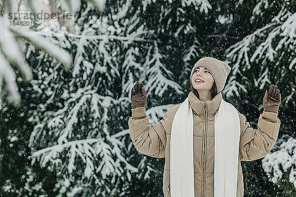 Junge Frau trägt warme Kleidung im Schneefall im Park