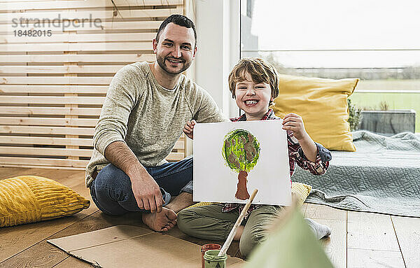 Glücklicher Vater mit Sohn  der zu Hause Baummalerei zeigt