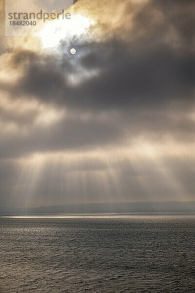 Sunlight falling on seascape through storm clouds at sunset