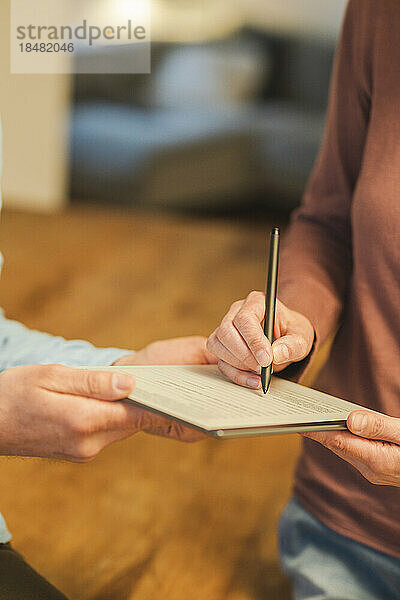 Hand einer Frau  die eine Vereinbarung mit einem Stift unterzeichnet