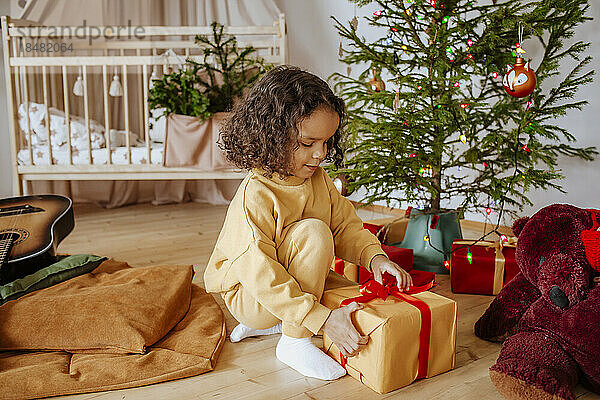 Nettes Mädchen  das zu Hause Geschenke unter dem Weihnachtsbaum öffnet