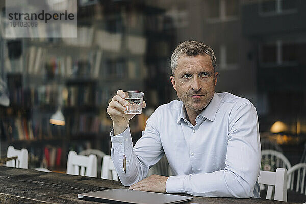 Geschäftsmann mit einem Glas Trinkwasser sitzt im Café