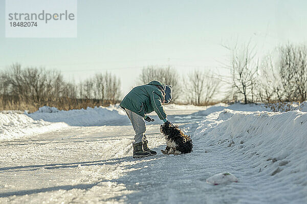 Junge spielt mit Hund im Schnee
