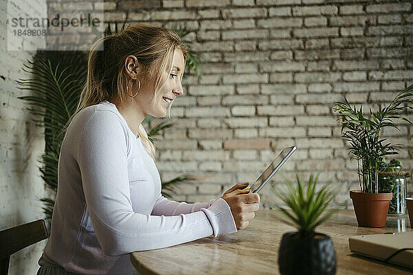 Lächelnde Geschäftsfrau mit Tablet-PC am Schreibtisch im Büro