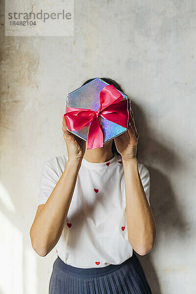 Frau bedeckt Gesicht mit Geschenkbox