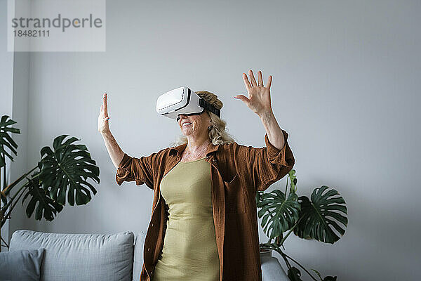 Lächelnde Frau  die Spaß daran hat  zu Hause ein Virtual-Reality-Headset zu tragen