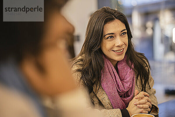 Lächelnde schöne Frau sitzt im Café