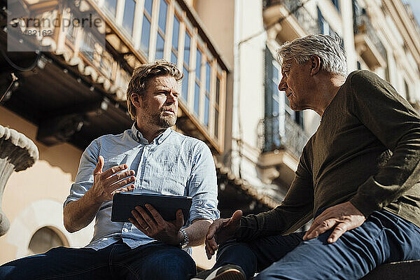 Reifer Mann diskutiert mit Vater vor dem Gebäude