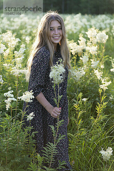 Lächelnde Frau  die inmitten blühender Pflanzen steht