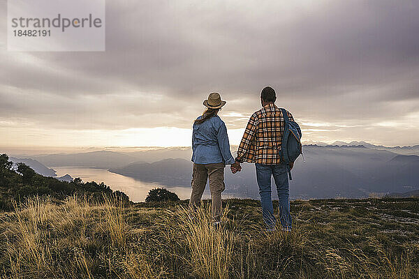 Älteres Paar hält Händchen und steht auf dem Berg