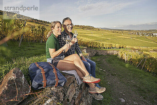 Glückliches Paar sitzt mit Weingläsern an der Wand