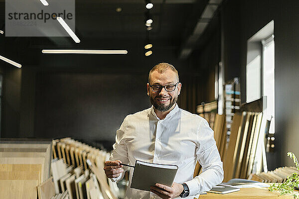 Porträt eines lächelnden Geschäftsmannes mit Buch im Architekturbüro