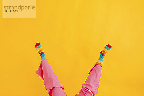 Feet of woman wearing multi colored socks against yellow background