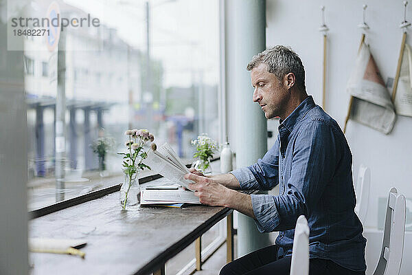 Geschäftsmann liest Zeitung und sitzt im Café