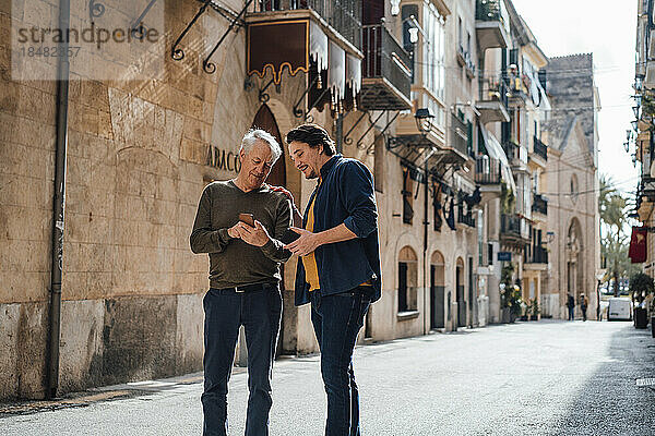 Vater und Sohn nutzen Smartphone auf der Straße