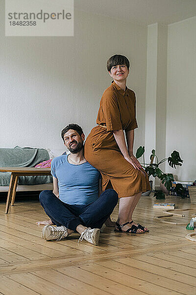 Reifer Mann mit gekreuzten Beinen von Frau im heimischen Wohnzimmer