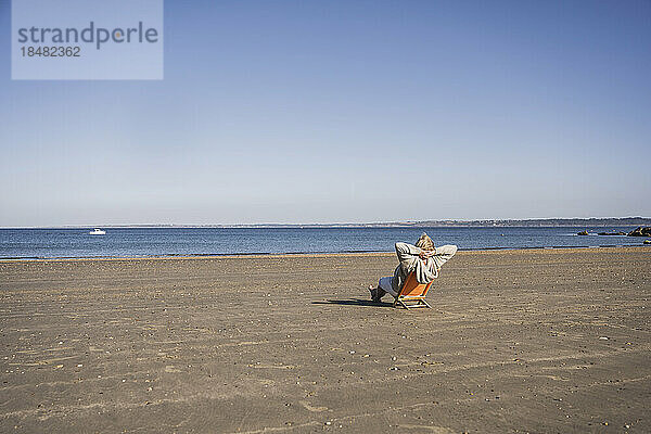 Ältere Frau entspannt sich und blickt an einem sonnigen Tag auf das Meer