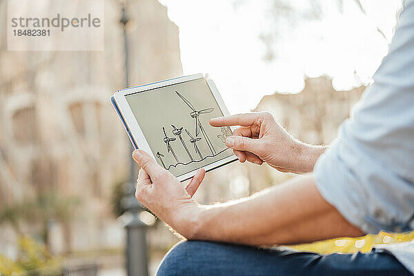Reifer Mann untersucht das Diagramm einer Windkraftanlage auf einem Tablet-PC