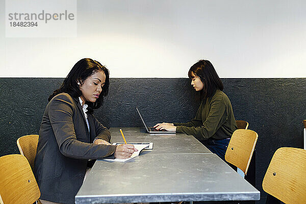 Geschäftsfrauen arbeiten zusammen und sitzen am Schreibtisch im Büro