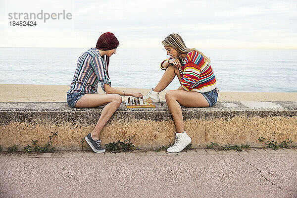 Freunde spielen Schach an der Promenade vor dem Meer