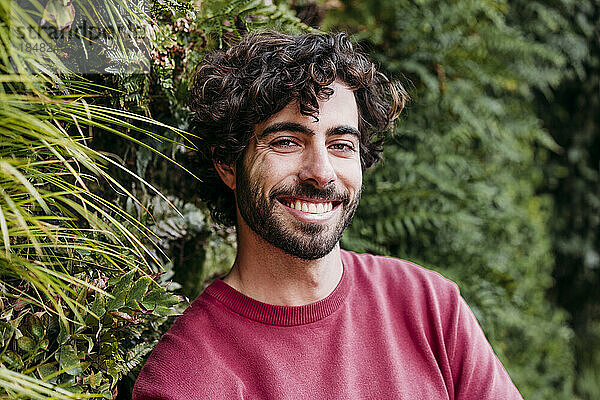 Lächelnder junger Mann vor Pflanzen