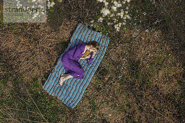 Woman relaxing on mattress at garden
