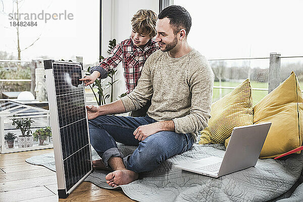 Sohn berührt Solarpanel von Vater zu Hause