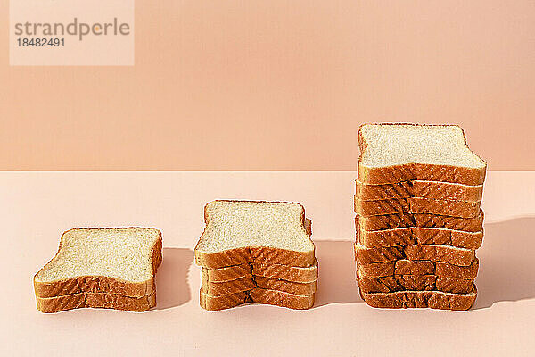 Brotscheiben auf pfirsichfarbenem Hintergrund gehalten