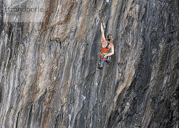 Sportlerin klettert mit Klettergurt auf Felsen